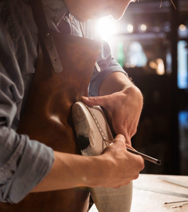 Cobbler doing measurments on a shoe with tape at his workshop