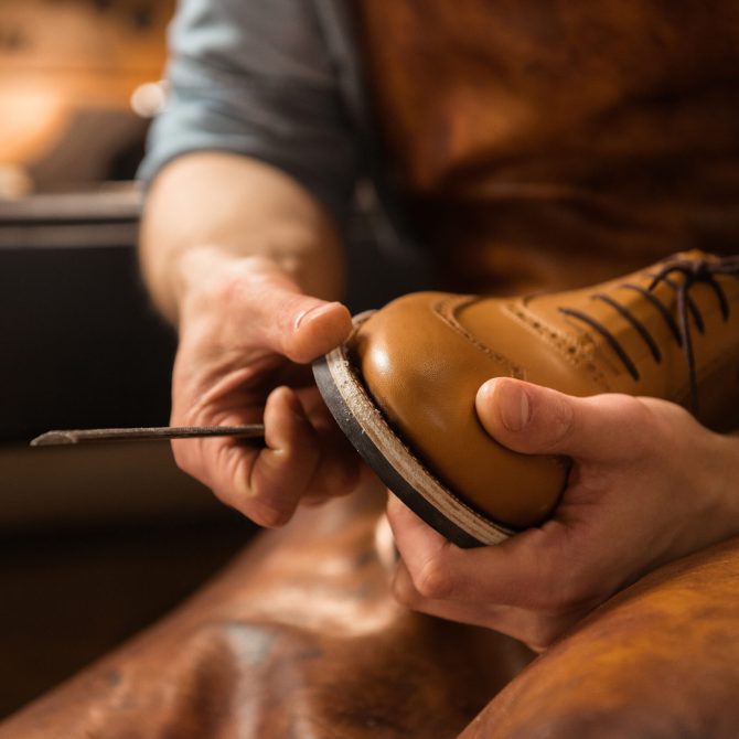 Cropped image of young shoemaker in workshop making shoes.