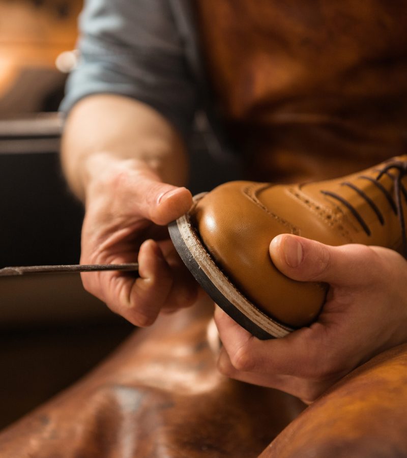 Cropped image of young shoemaker in workshop making shoes.